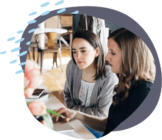 two girls collaborating at a desk on the computer