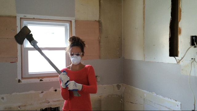 Lindsay Ostrom holding an axe and working on house demolition
