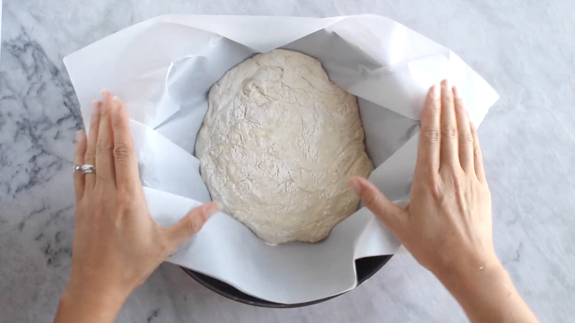Screenshot from a video showing hands about to knead dough