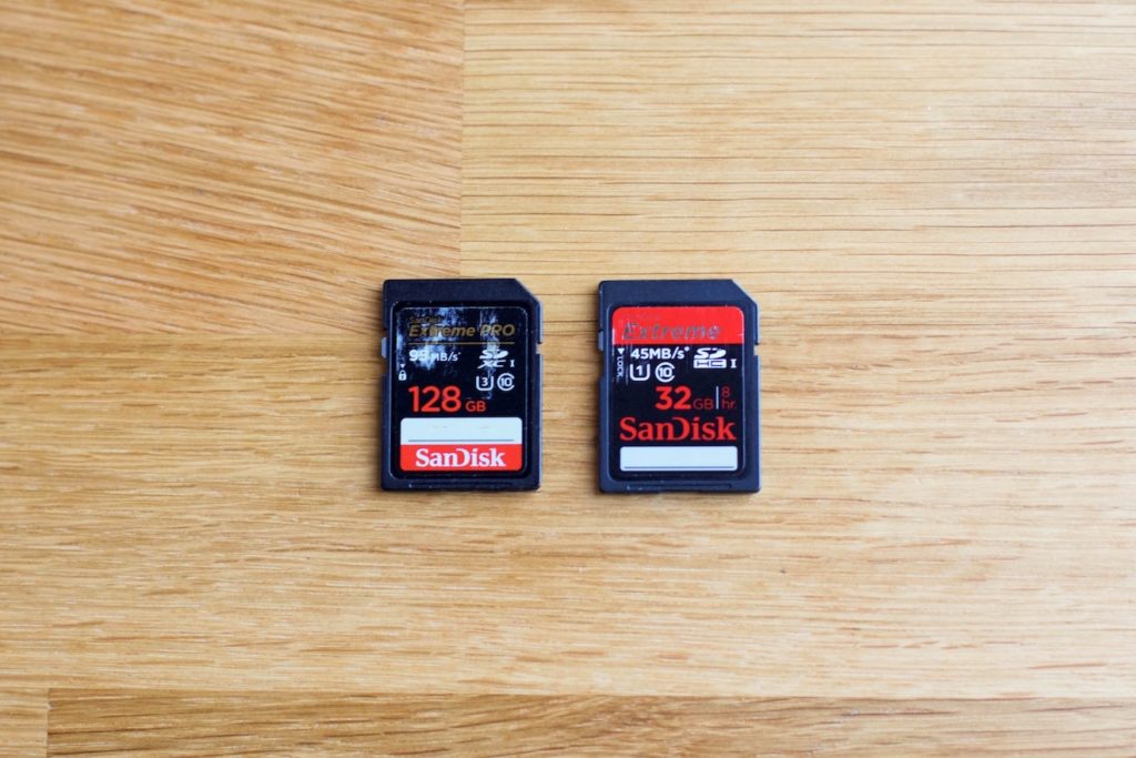 A 128 GB SanDisk Extreme Pro memory card and a 32 GB SanDisk Extreme Pro memory card on a wood table