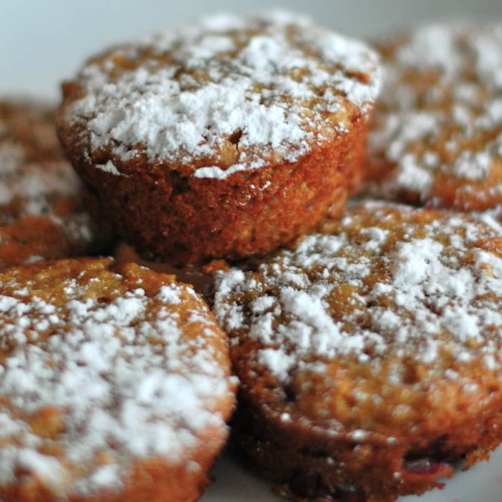 Muffins stacked on top of each other with powdered sugar sprinkled on top