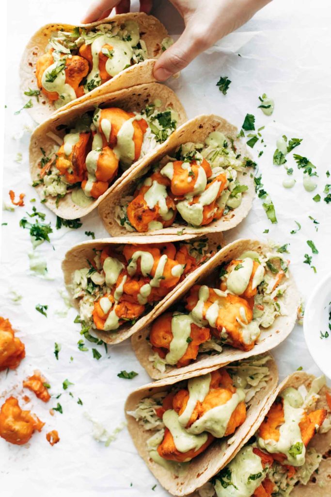 Seven tacos loaded with ingredients photographed from overhead