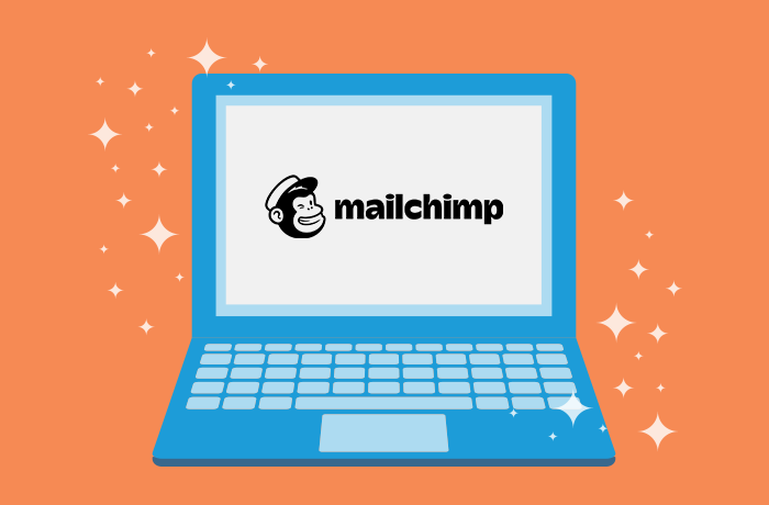 Graphic of blue laptop in front of an orange background with the Mailchimp logo on the screen