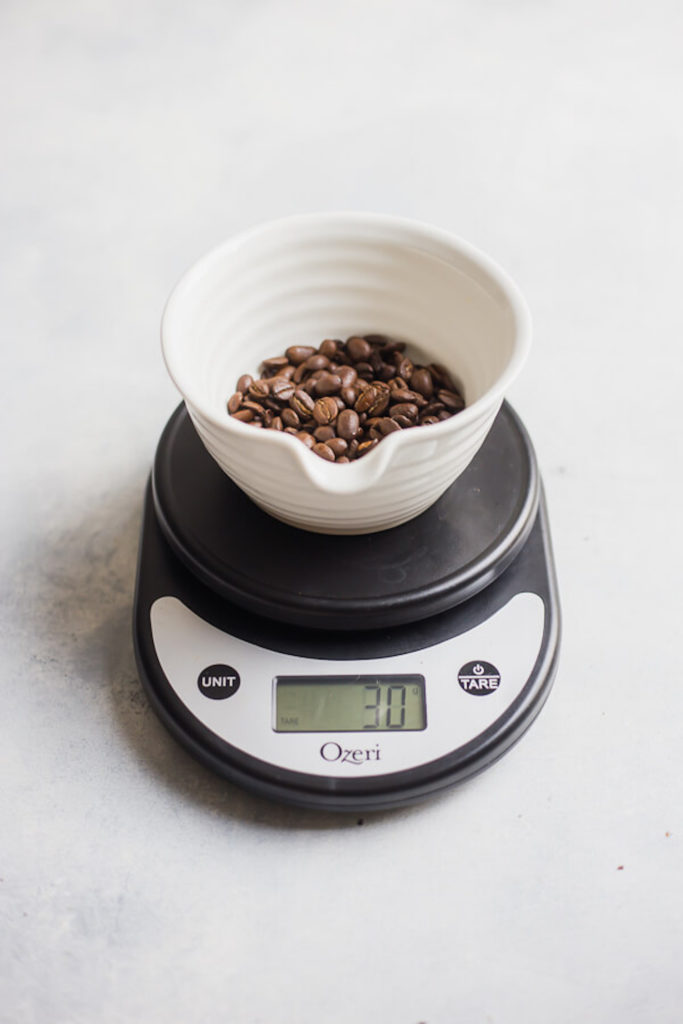 Cup of coffee beans on a digital scale that reads '30g'