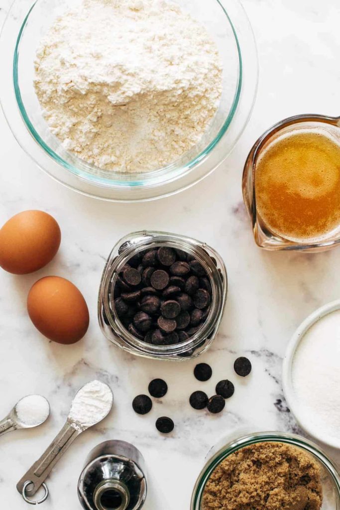 Various ingredients like eggs, sugar, brown sugar, etc. on top of a marble kitchen counter