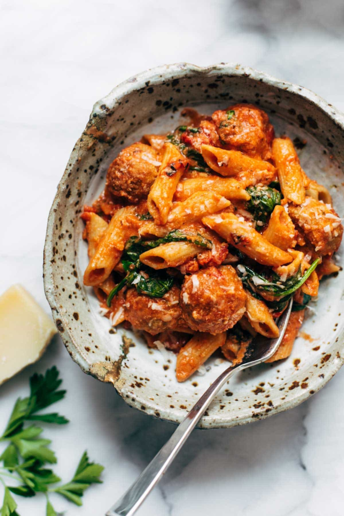 a bowl of penne pasta with meatballs