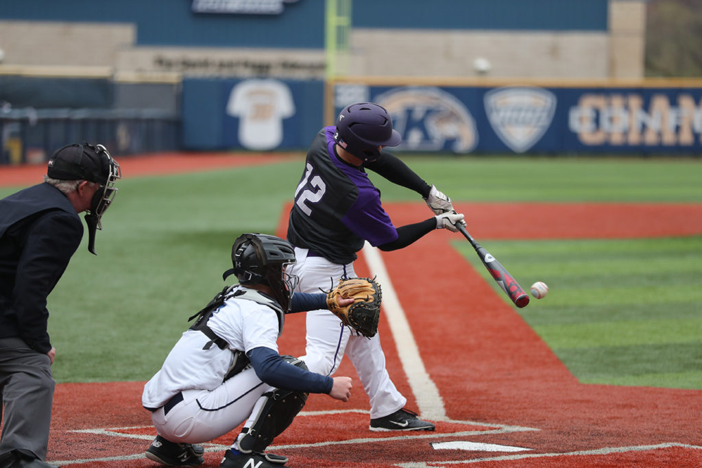 A baseball player in the middle of hitting a baseball