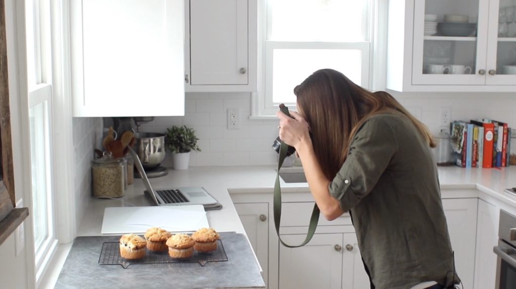 Lindsay Ostrom taking a food photo of muffins with backlit natural light