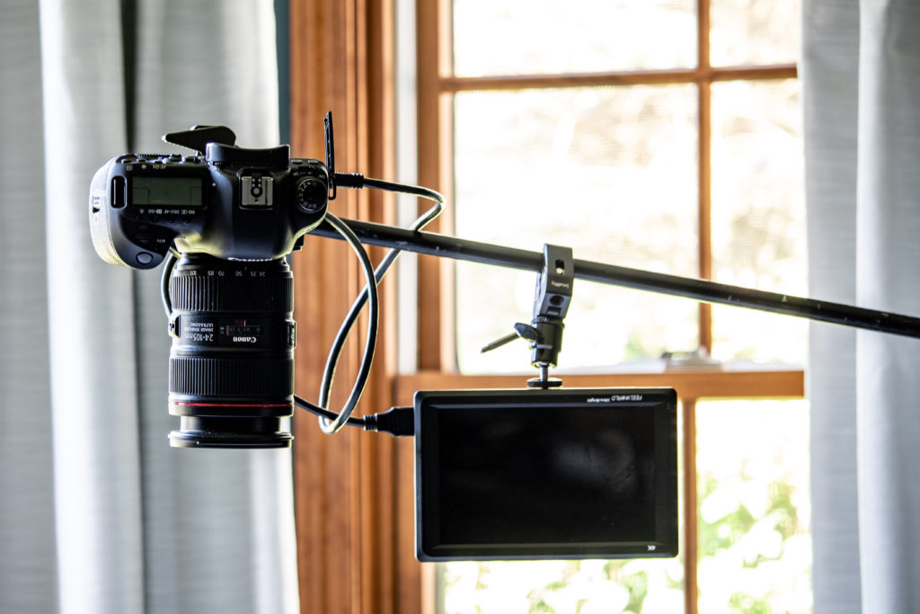 Close-up of the Impact C-Stand with Sliding Leg Kit holding a Canon DSLR camera and FeelWorld Ultra-Bright Monitor, set-up for an overhead photograph.