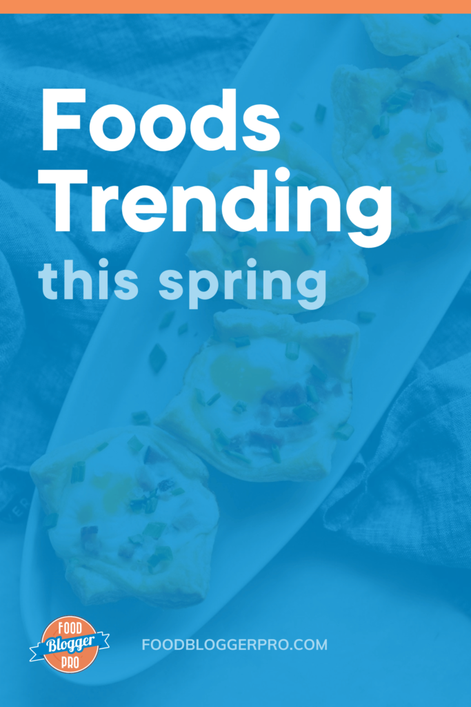 Photograph of ham, egg, and cheese cups on a white plate sitting on top of a towel. The image reads "foods trending this spring" with the Food Blogger Pro logo in the bottom left corner and foodbloggerpro.com across the bottom.