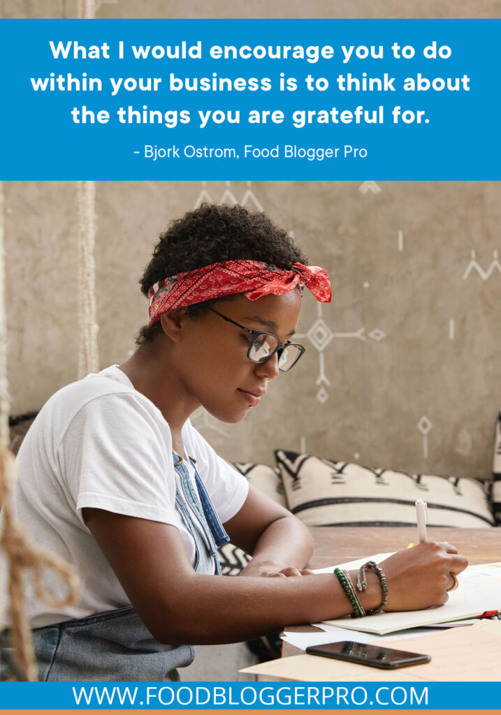 A photograph of a woman writing at a desk with a quote from Bjork Ostrom's episode of The Food Blogger Pro Podcast that reads: "What I would encourage you to do within your business is to think about the things you are grateful for."